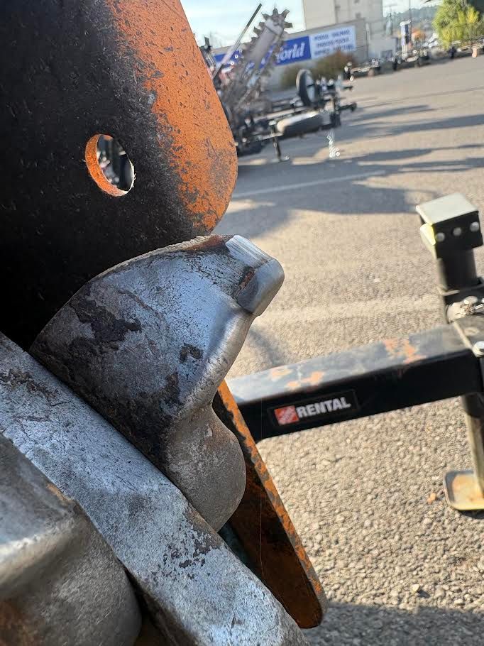 Close-up of a stump grinder tooth on a rental machine: the carbide tip is rounded over and polished smooth instead of ending in an edge