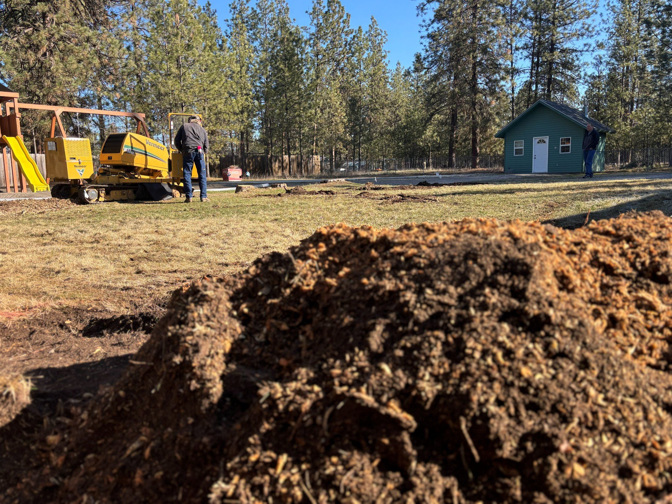 Chip pile with the stump grinder and crew working in the background
